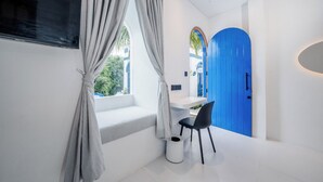 Une pièce moderne avec un bureau blanc, une chaise noire, une porte bleue et une fenêtre avec des rideaux.