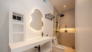 Une salle de bain moderne avec un meuble-lavabo blanc, des toilettes et un espace douche.