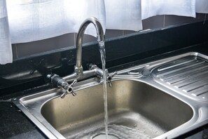 A stainless steel kitchen sink with a faucet and a strainer. -  Brickwood Apartments (Nairobi)