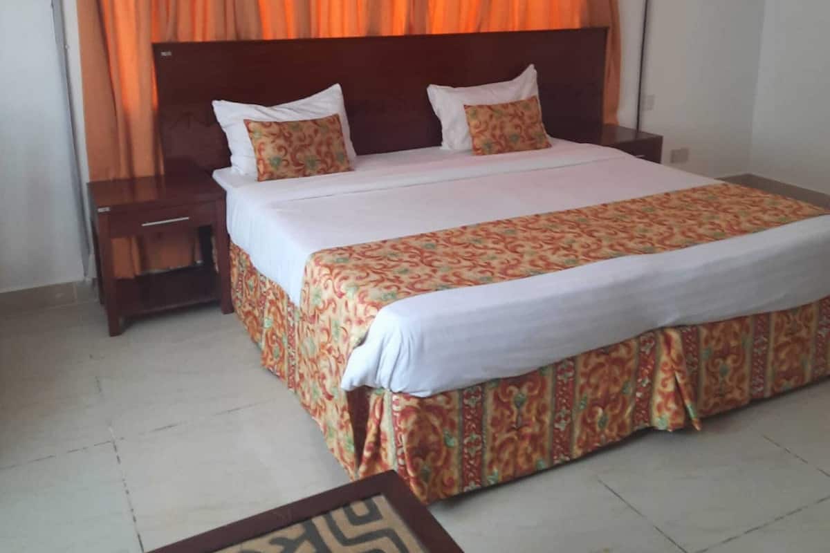 Habitación de hotel con cama, mesita de noche y ventilador de techo.