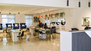 Un'accogliente sala moderna con diverse zone salotto, una reception e numerosi specchi e piante.