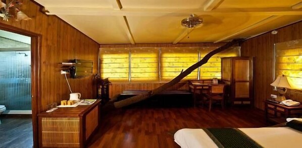 A wooden room with a bed, a desk, a chair, and a staircase. - The Tree House Resort (Amer)