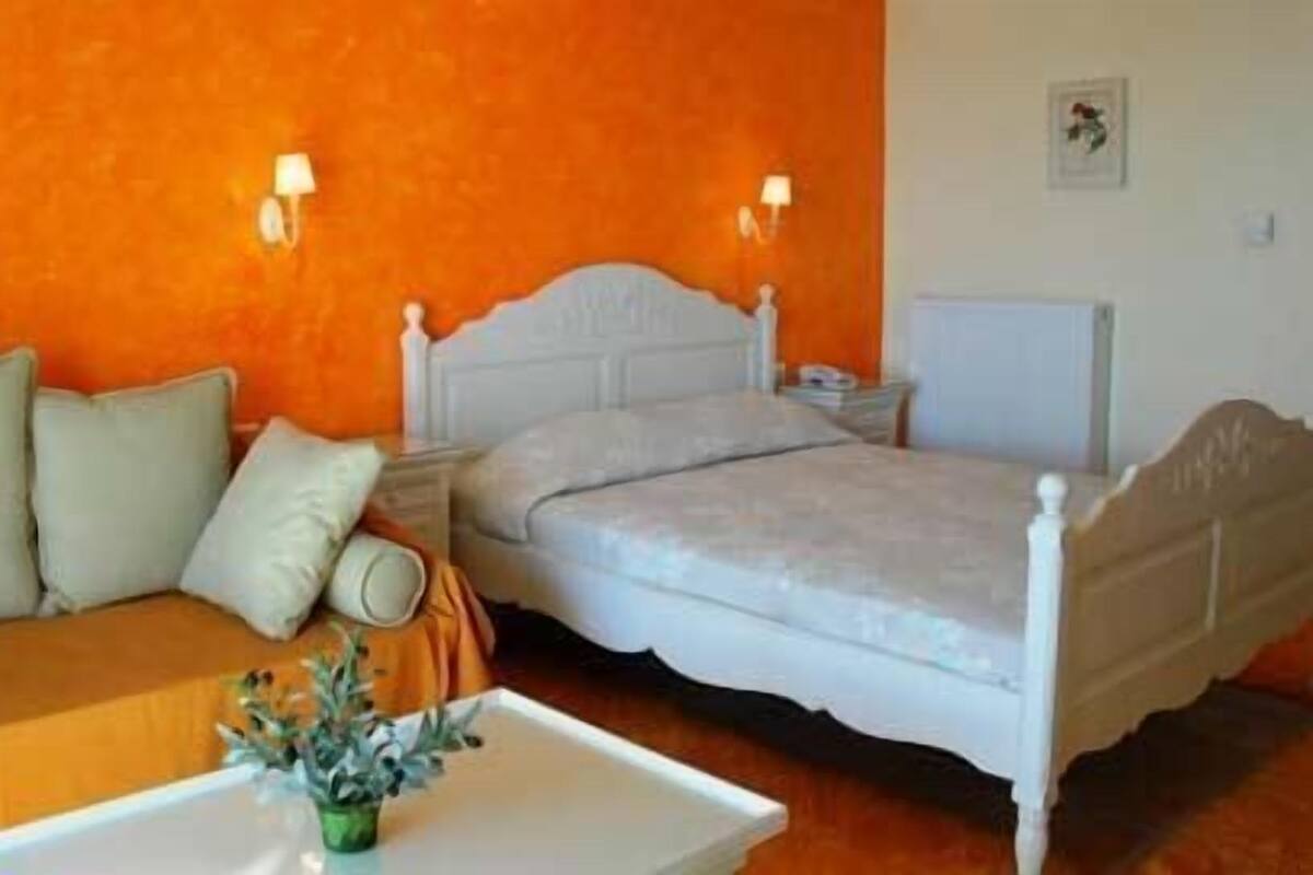 Ein Schlafzimmer mit einem Bett, einem Schlafsofa und einem Nachttisch mit Lampe.
