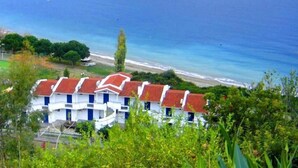 Un hôtel situé sur la côte, composé de plusieurs bâtiments, offrant une vue sur la plage et entouré d’une végétation luxuriante.