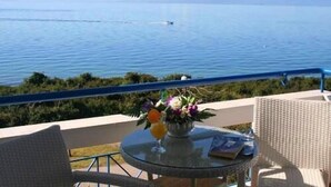 Un balcon avec une table en verre, des chaises en osier et un vase rempli de fleurs.