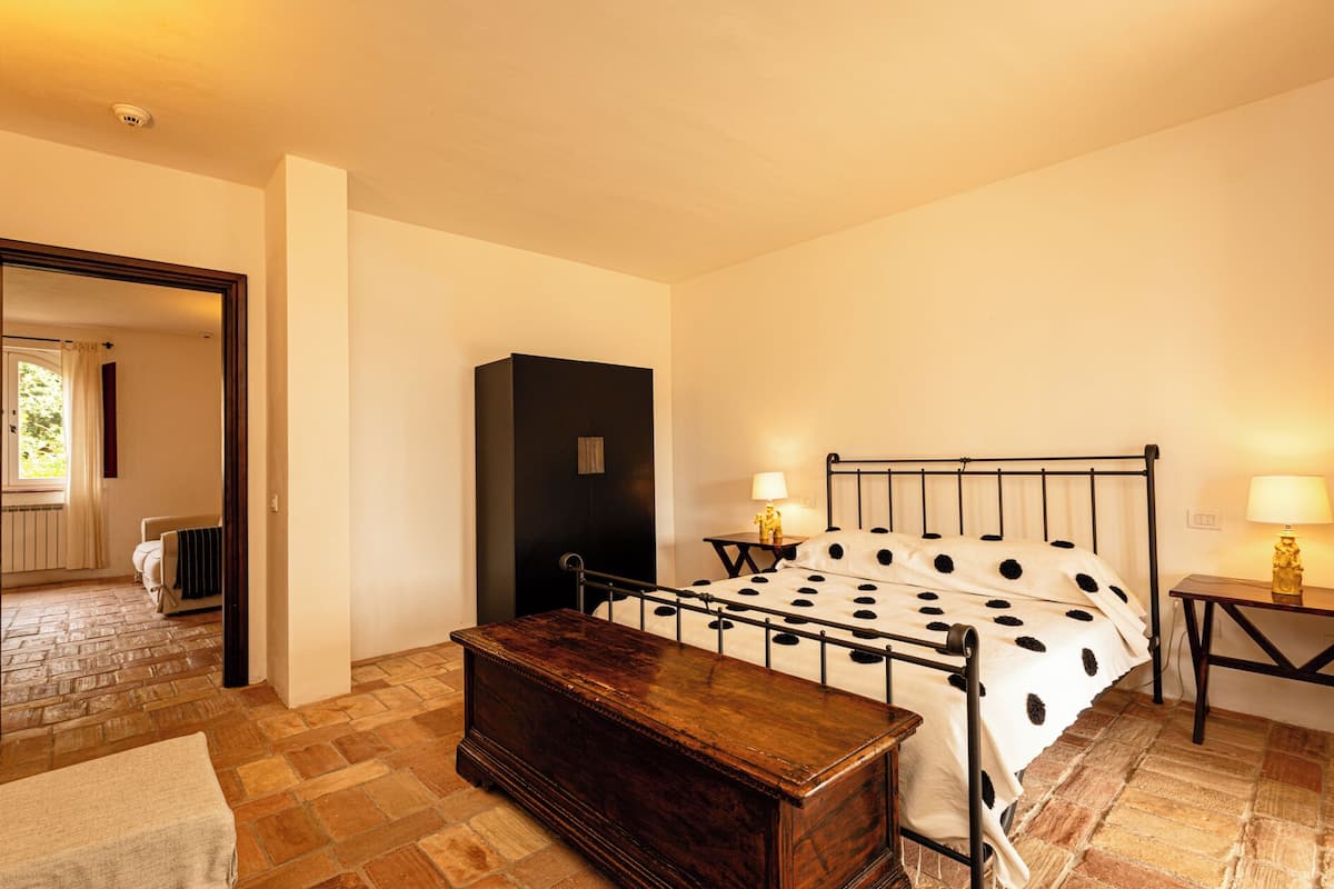 A bedroom with a bed, bedside tables, a wooden chest, and a wardrobe.