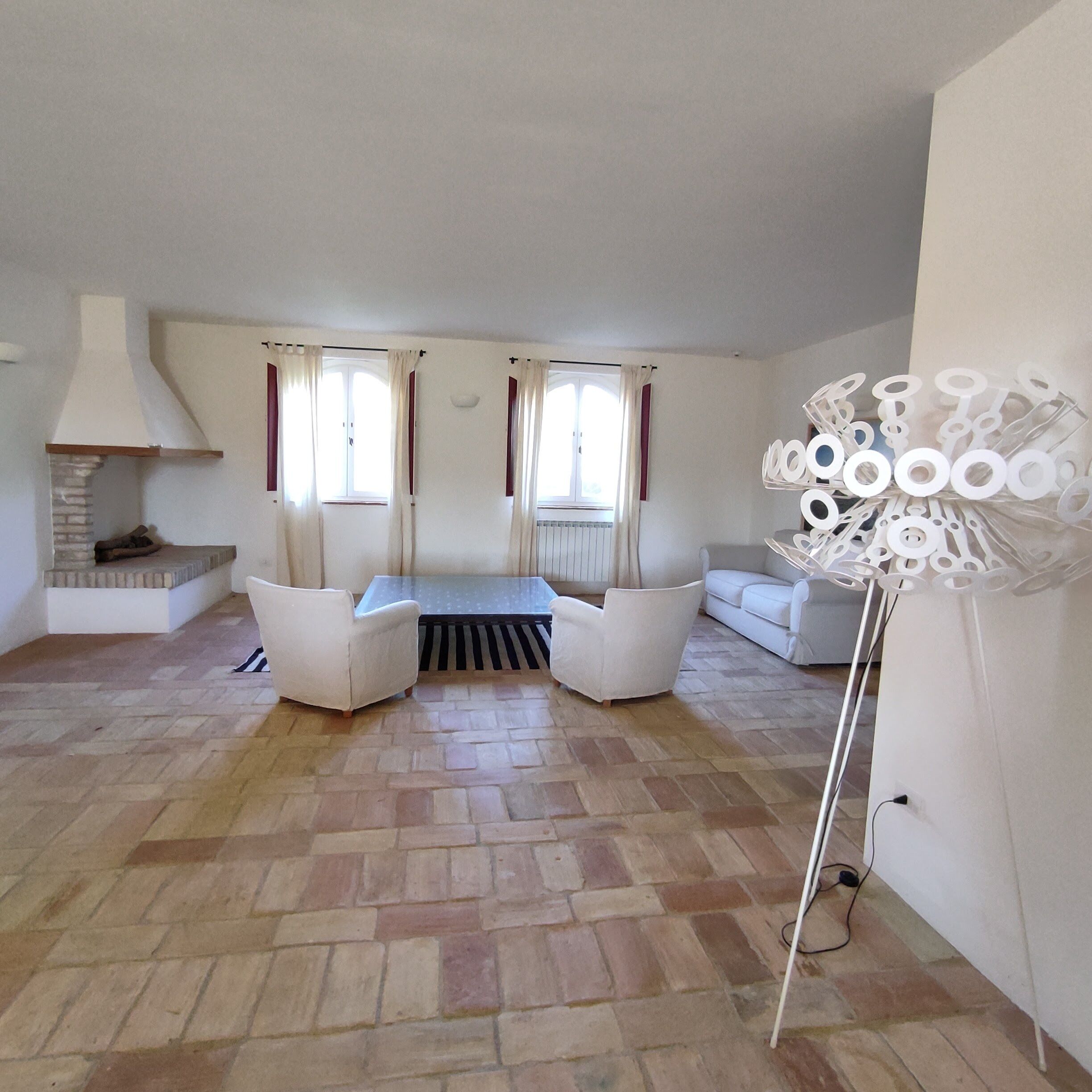 A spacious living room with a fireplace, a sofa set, and a decorative floor lamp.
