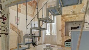 Un interior rústico con una escalera espiral, paredes de piedra y una chimenea.