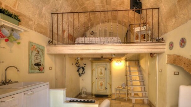 Cocina compacta con un lavamanos, un mueble pequeño y una escalera que sube a un nivel superior.