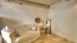 Una habitación con un sofá blanco, una mesita auxiliar y un adorno en la pared.