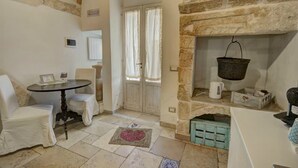 Una habitación acogedora con chimenea de piedra, una mesita, dos sillas y una puerta con cortinas.