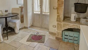 Una habitación acogedora con una chimenea de piedra, una mesa con sillas y una puerta con cortinas.
