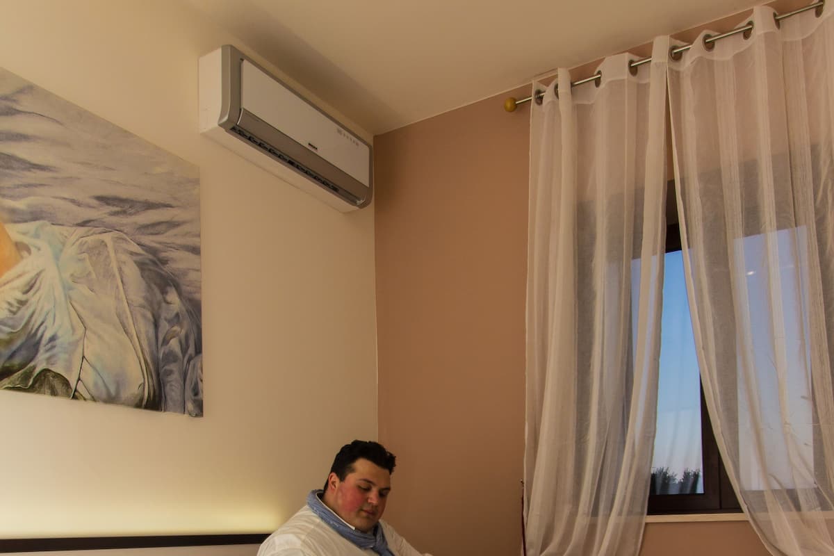 A hotel room with a bed, a laptop, a tray with breakfast items, and a painting on the wall.