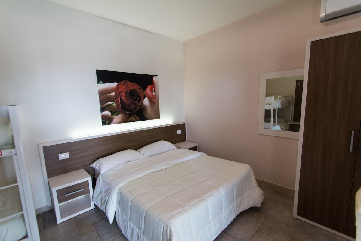 A bedroom with a bed, a nightstand, a wardrobe, and a wall-mounted picture.
