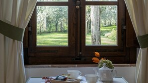A window with a view of a green landscape, a table with a teapot, cups, and a tray of snacks. - Podere La Rocca (Montepulciano)