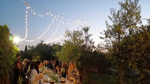 An outdoor dining area with string lights, tables set for a meal, and a natural backdrop. - Podere La Rocca (Montepulciano)
