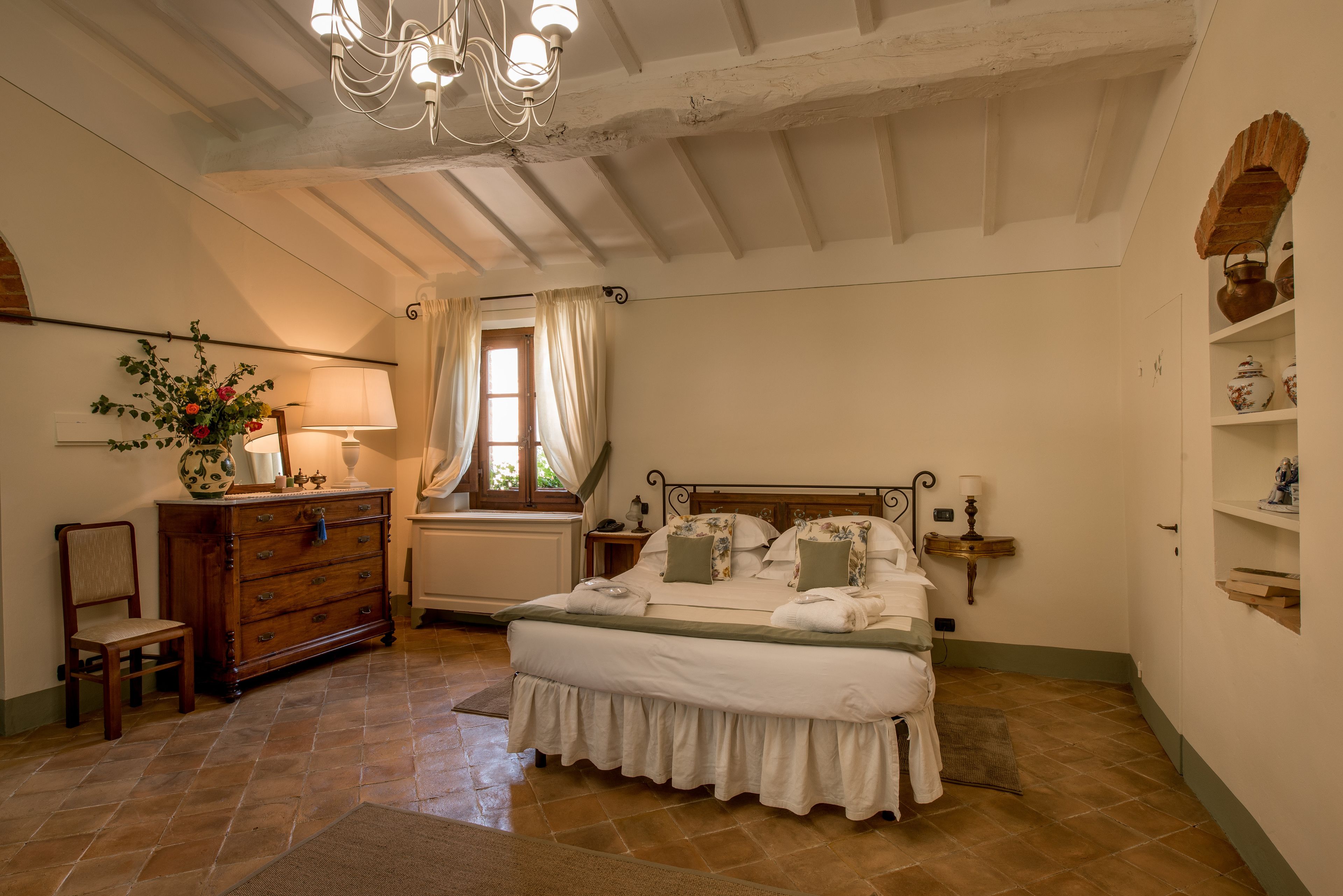 A bedroom with a large bed, wooden dresser, and a chandelier.