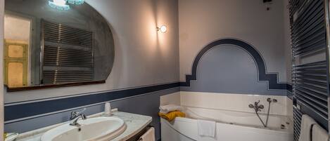 A bathroom with a sink, mirror, and bathtub.