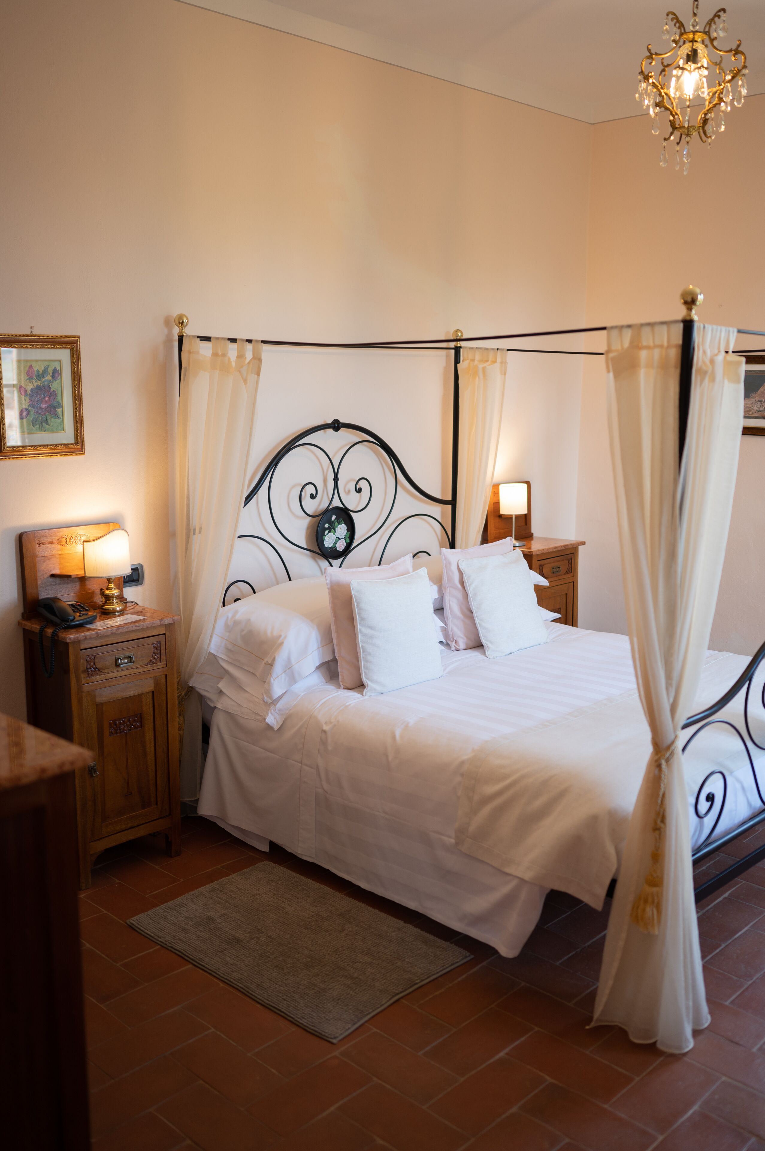 Una cama bien hecha con ropa blanca, una mesita de noche con una lámpara y un cabecero decorativo.