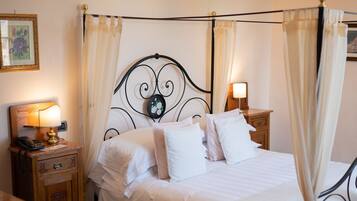 Una cama bien hecha con ropa blanca, una mesita de noche con una lámpara y un cabecero decorativo.