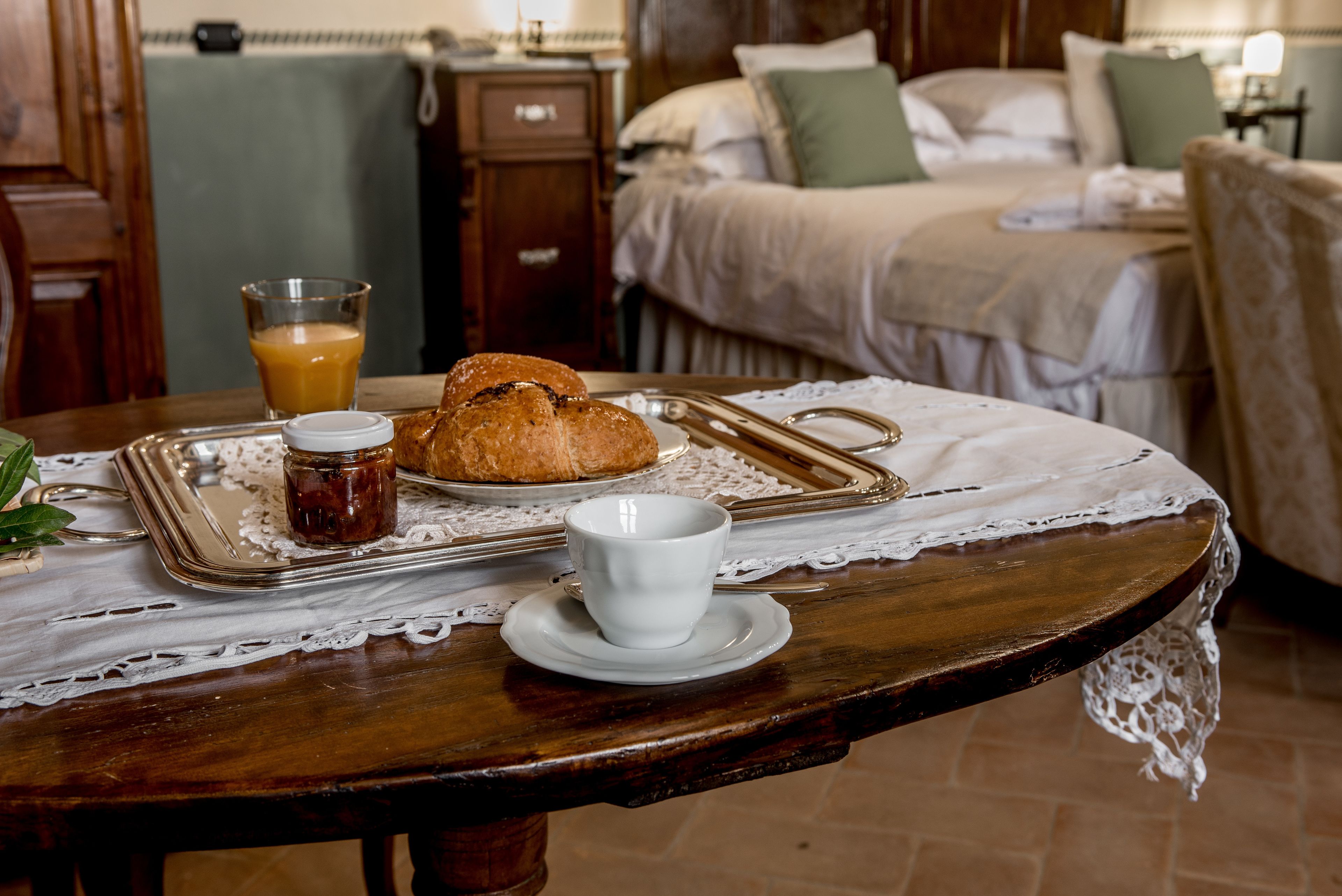 A breakfast setup with bread, a cup, and a glass of orange juice on a wooden table.