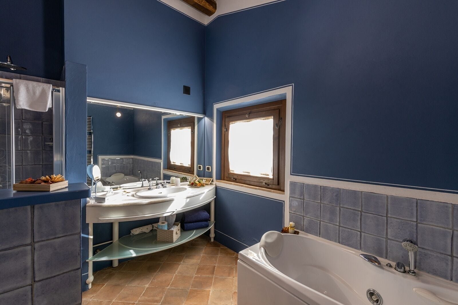 A bathroom with blue walls, a white bathtub, and a vanity with a mirror.