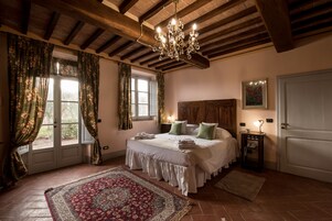 Un dormitorio con una cama grande, cabecera de madera, candelabro, mesita de noche y alfombra roja.