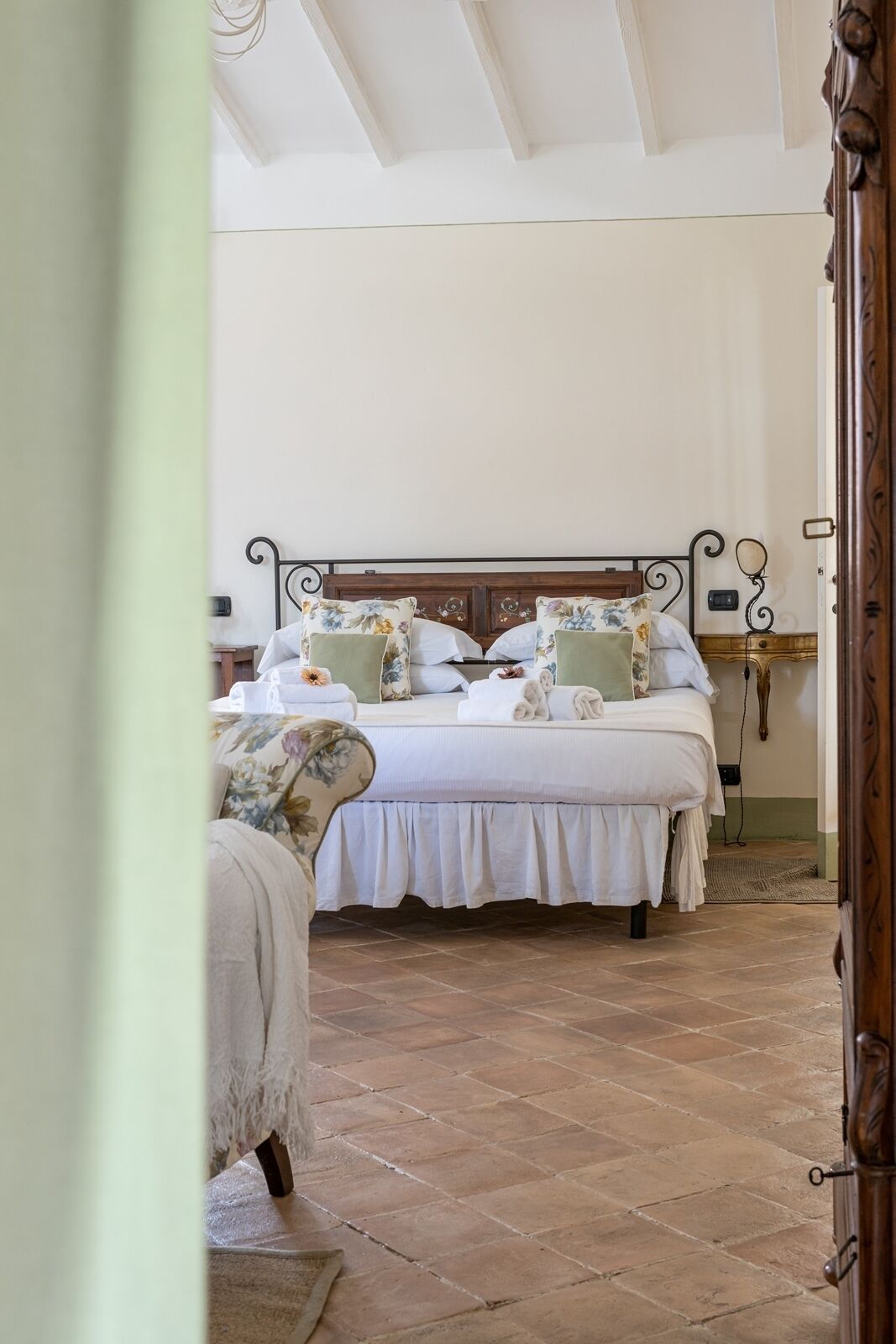 Een slaapkamer met een houten bed, bloemenbedekking en een betegelde vloer.