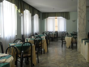 Guests can dine in comfort at this elegant space, surrounded by tables and chairs with green cushions.
