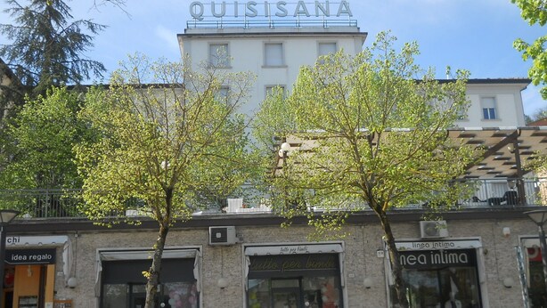 A building with a sign reading "QUISISANA" and storefronts below. - Hotel Quisisana (Chianciano Terme)
