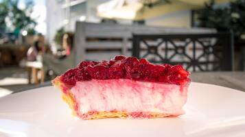 Una porción de pastel de queso con cobertura de frutos rojos sobre un plato blanco.