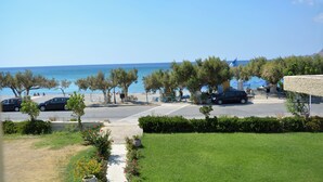 A coastal view with parked cars, a pedestrian crossing, and a clear sky. - Galini Beach (Agios Vasileios)