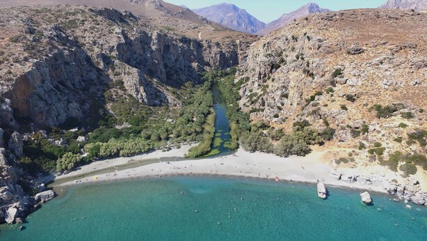 A coastal landscape with a narrow valley, rocky terrain, and clear turquoise waters. - Galini Beach (Agios Vasileios)