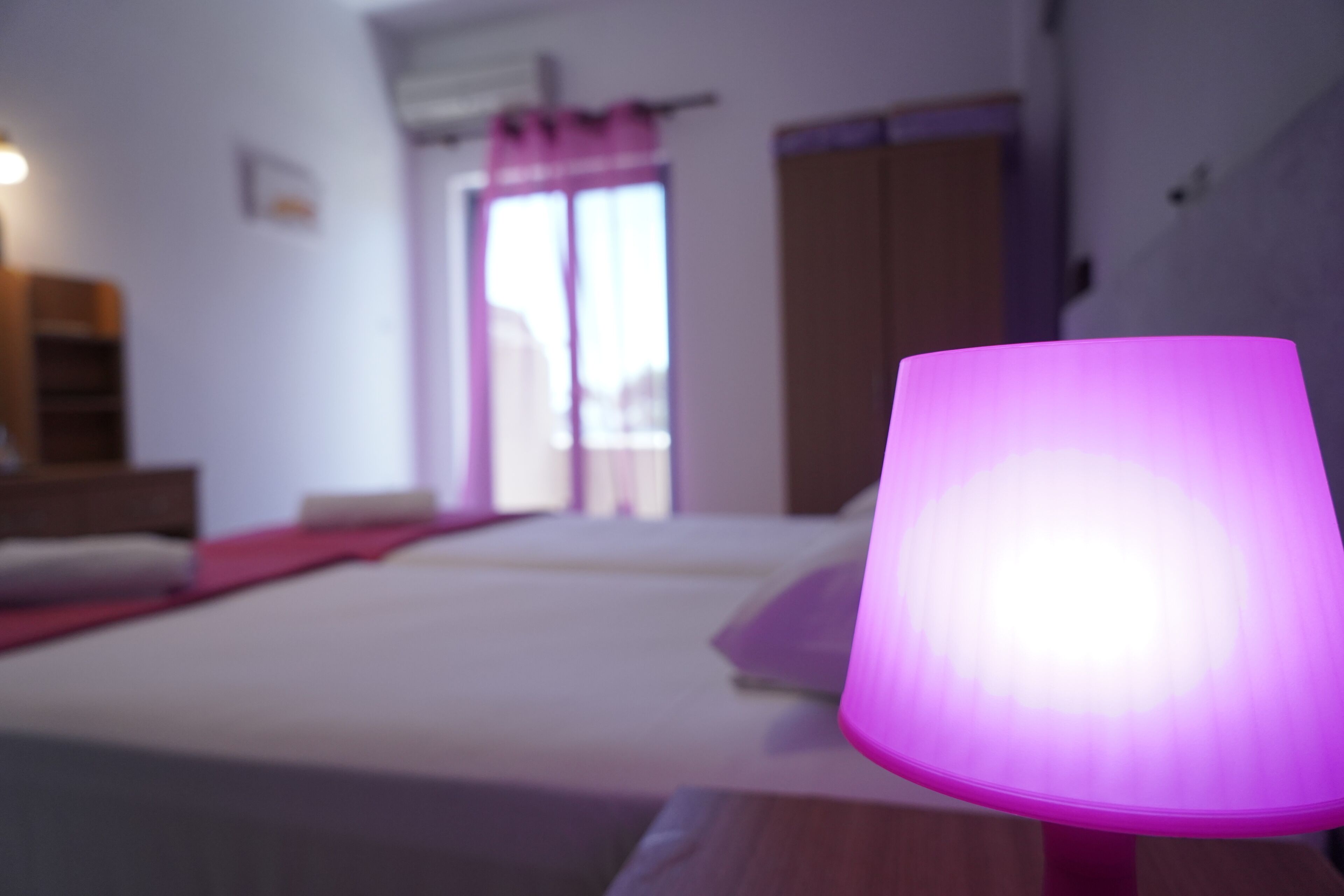 A bedroom with a bed, a bedside table, and a window with curtains.