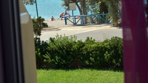 A view of a beach with a sign, trees, and a railing. - Galini Beach (Agios Vasileios)