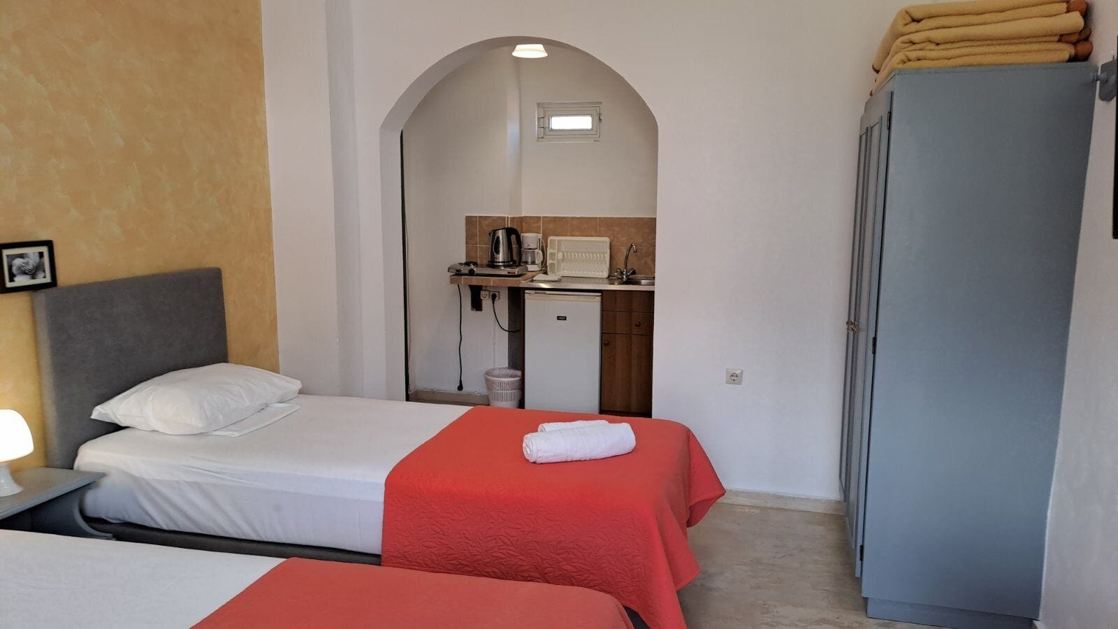 Habitación de hotel con dos camas, una kitchenette y un armario.