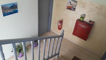 A staircase with a grey railing, a fire extinguisher mounted on the wall, and a red cabinet with a welcome sign.
