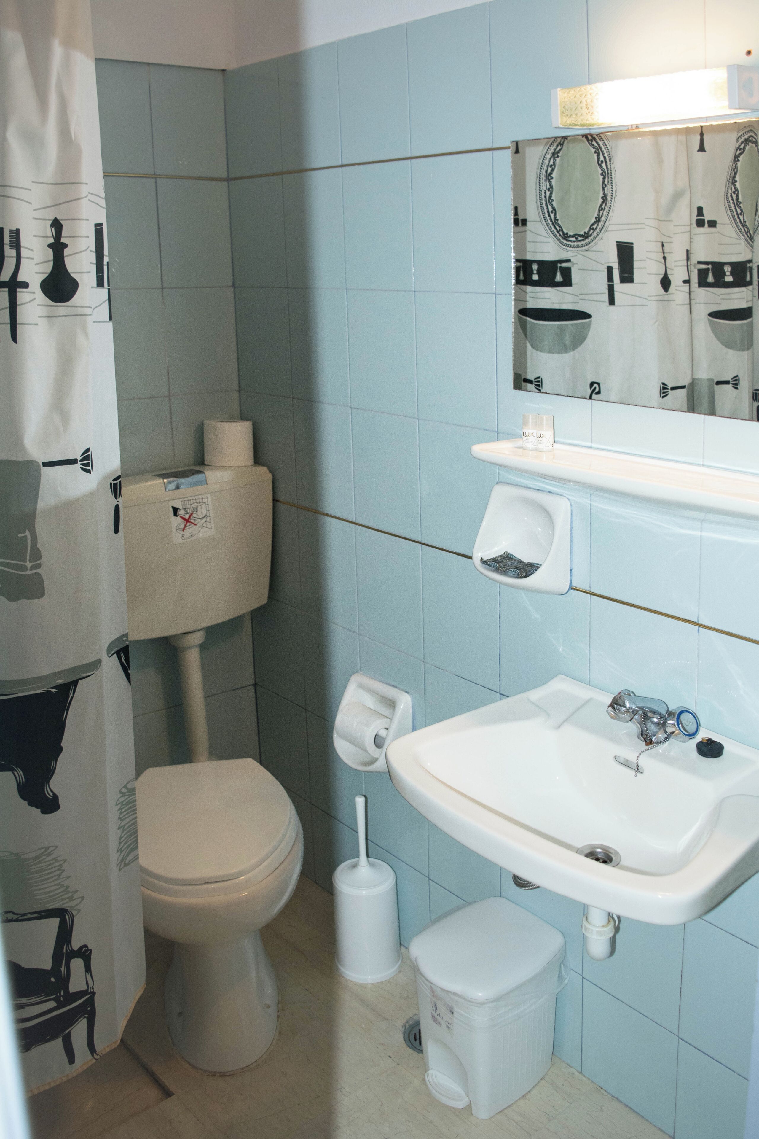 Een badkamer met toilet, bidet, wastafel en spiegel.