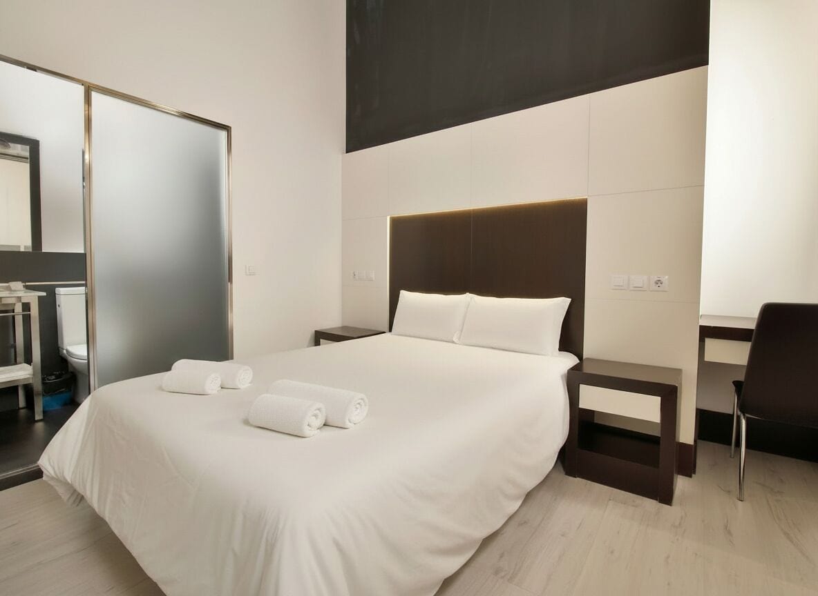 Ein Hotelzimmer mit einem großen Bett, einem Schreibtisch, einem Sessel und einem Spiegel.