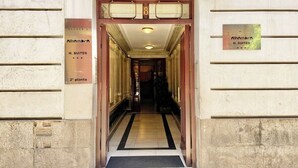 L’entrée d’un hôtel, avec une enseigne indiquant « Alhambra H. SUITES » et le chiffre « 8 » au-dessus de la porte.