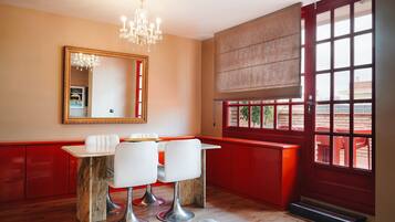 Una habitación con una decoración en tonos rojos y beige, un candelabro, un espejo grande y una ventana con vistas a un área de estar al aire libre.