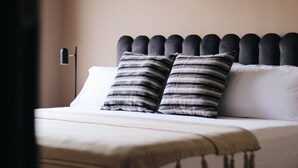 A neatly made bed with striped pillows and a plain headboard. - Isabella's House (Barcelona)