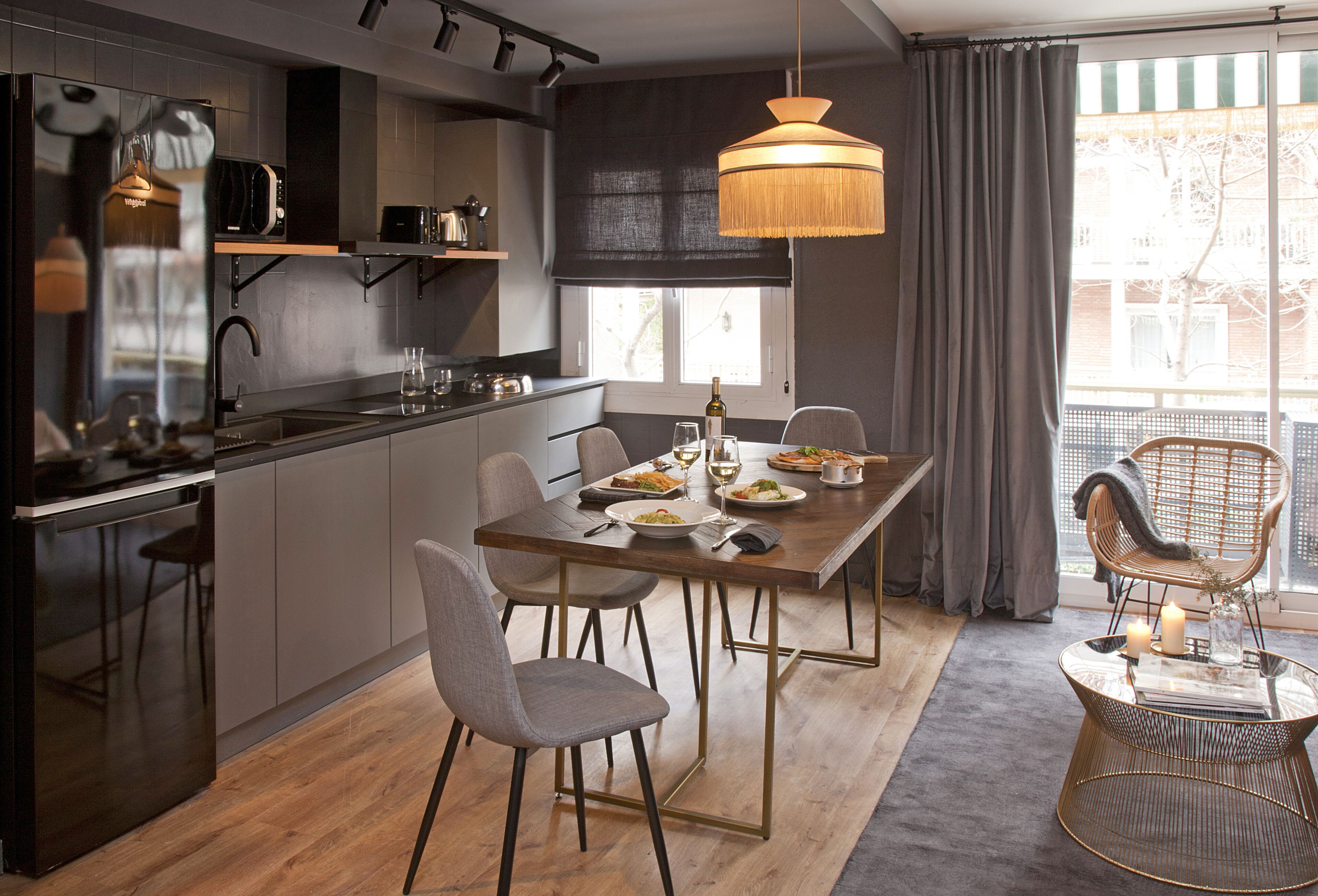 Une cuisine moderne avec un coin repas, comprenant une table en bois, des chaises et un luminaire suspendu.