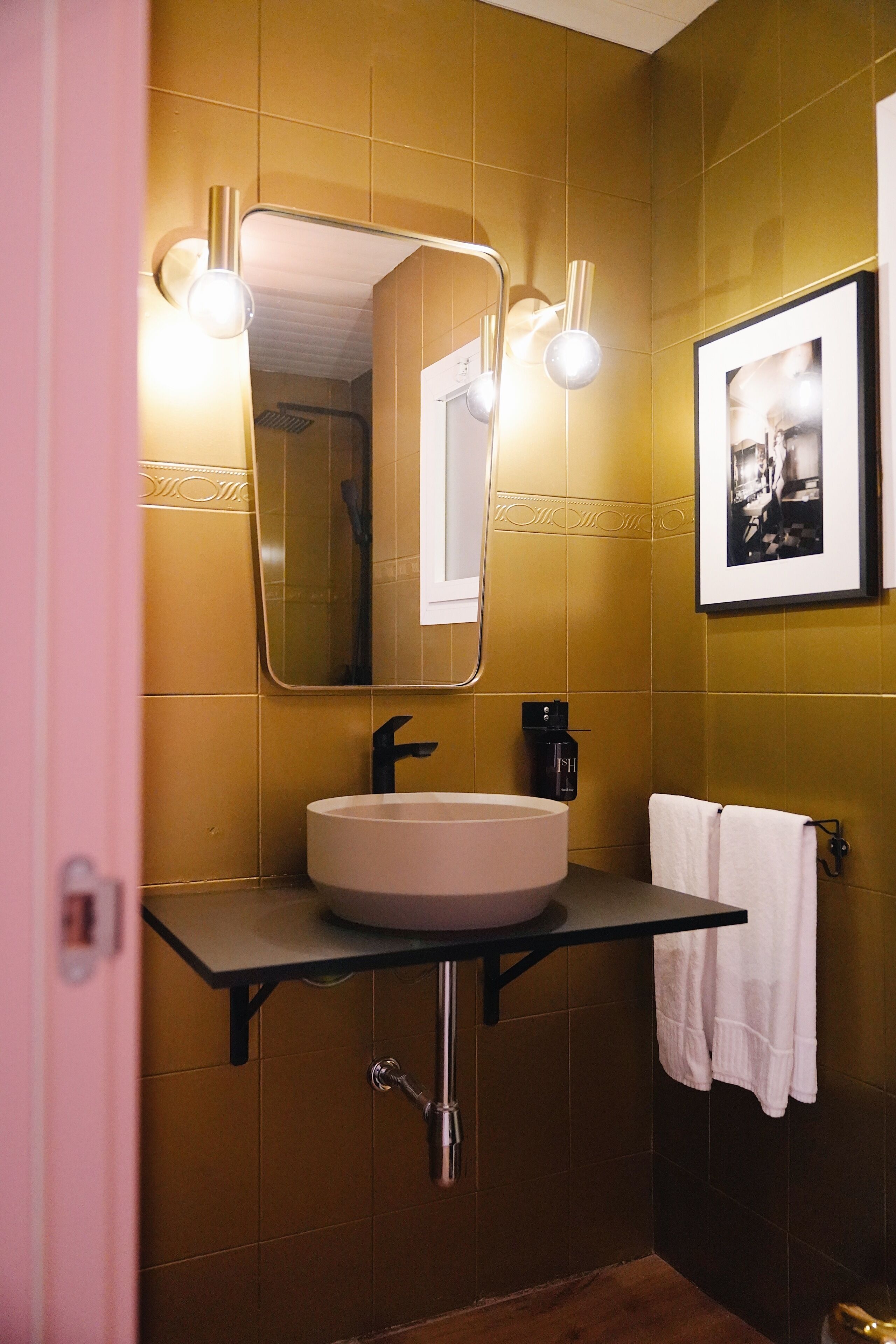 Un baño con lavamanos, espejo y toallero.
