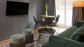 A modern living room with a green sofa, a round coffee table, and a dining area with chairs and a vase of flowers. - Isabella's House (Barcelona)