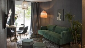 A modern living room with a green sofa, round ottomans, a woven coffee table, and a large floor lamp. - Isabella's House (Barcelona)