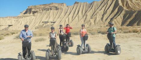A group of people on Segways in a desert landscape with rocky cliffs.