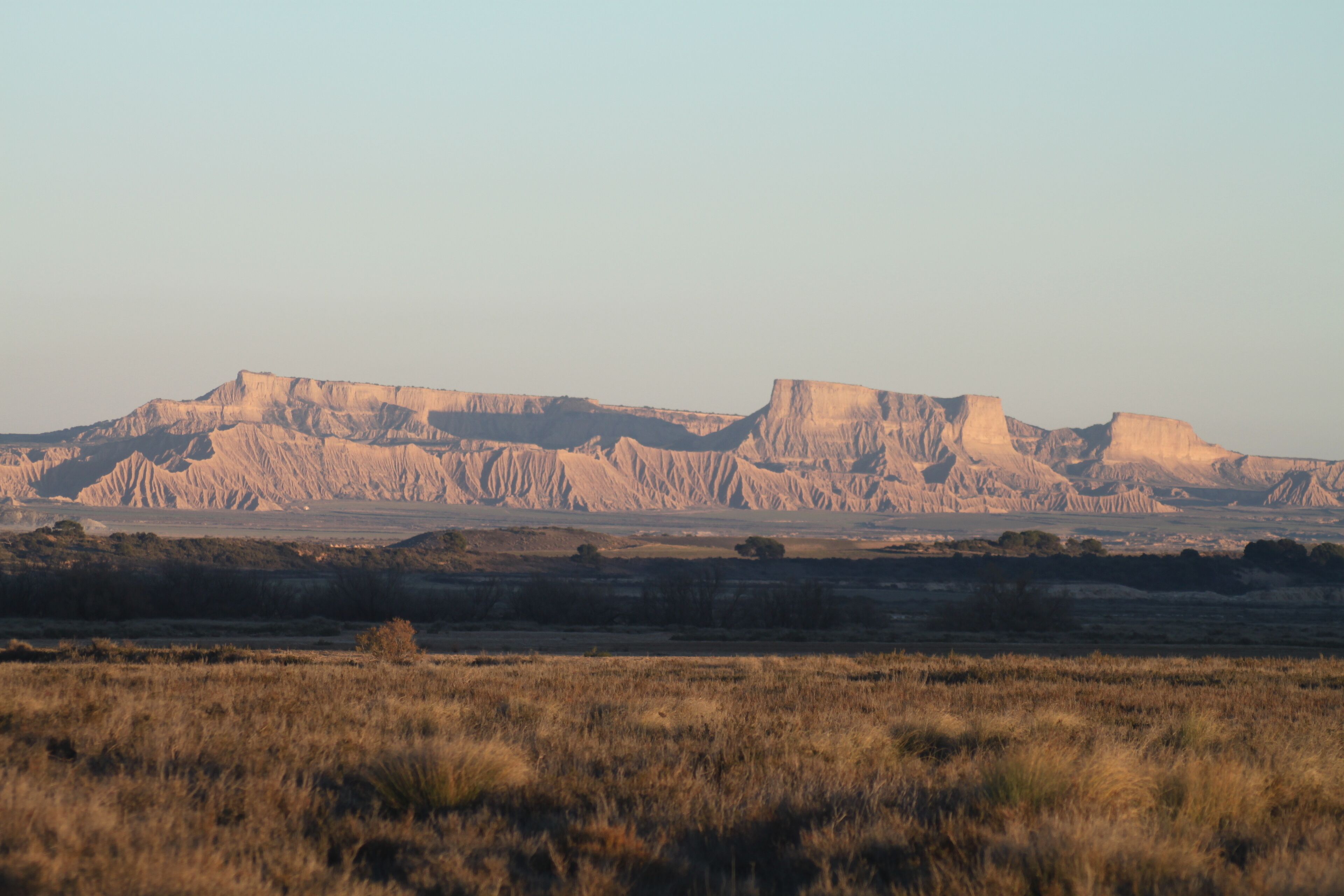 Un paisaje llano con una gran colina de cima plana al fondo.