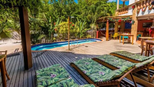 A poolside area with lounge chairs, a pool, and a bar area with outdoor seating. - Pousada Bahia Brasil (Cairu)