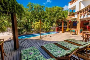 A poolside area with lounge chairs, a pool, and a bar area with outdoor seating. - Pousada Bahia Brasil (Cairu)